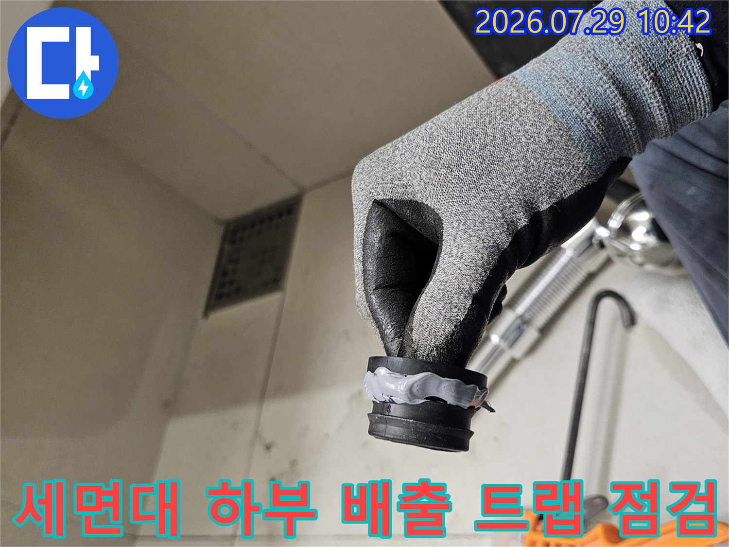 작업자가 세면대 아래쪽 배송용 트랩과 연결 파이프를 손으로 쥐고 확인하는 장면