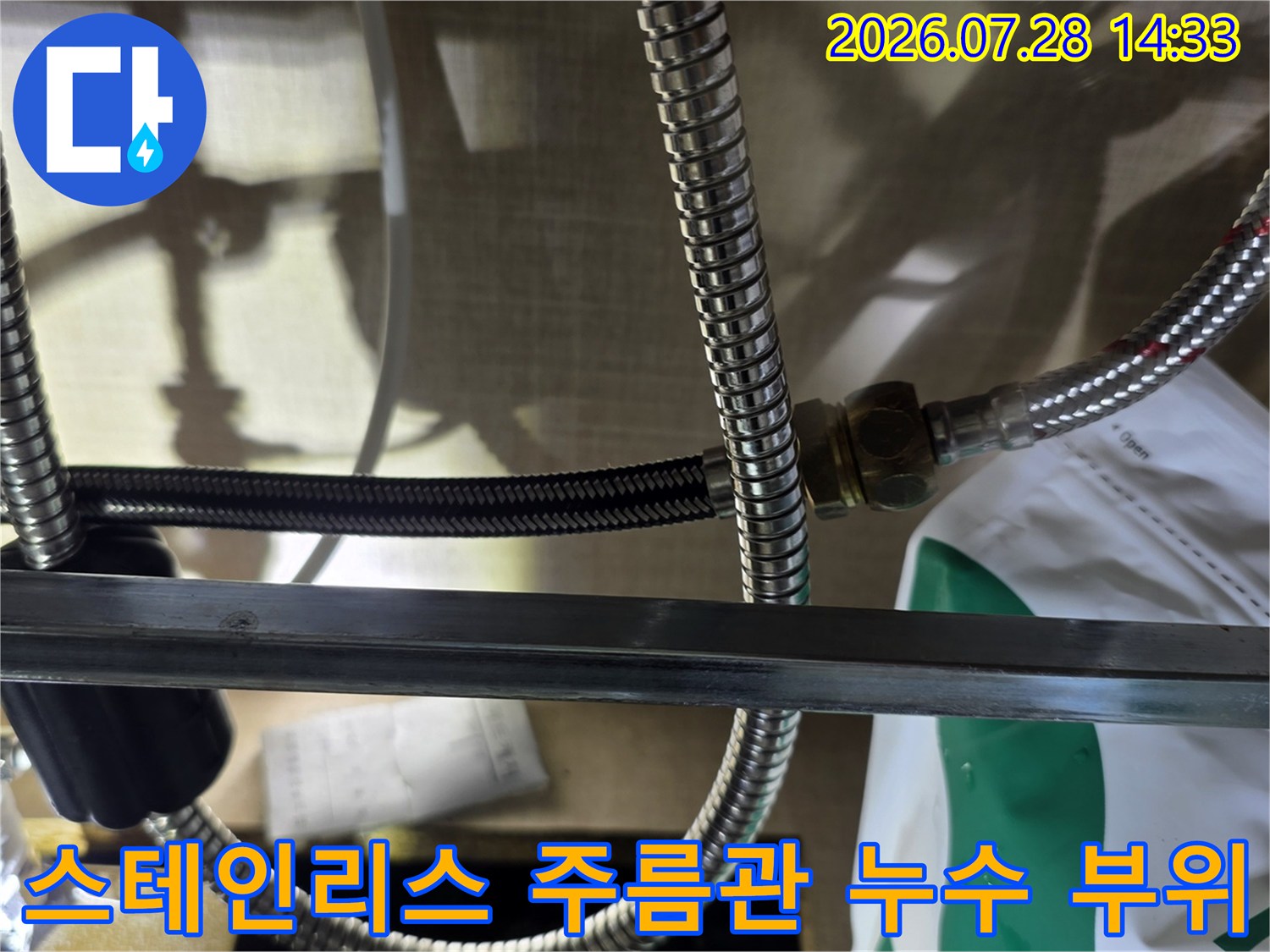 금속 배관 연결 너트 주변의 습기와 분리된 검은색 고무 패킹이 보이는 모습