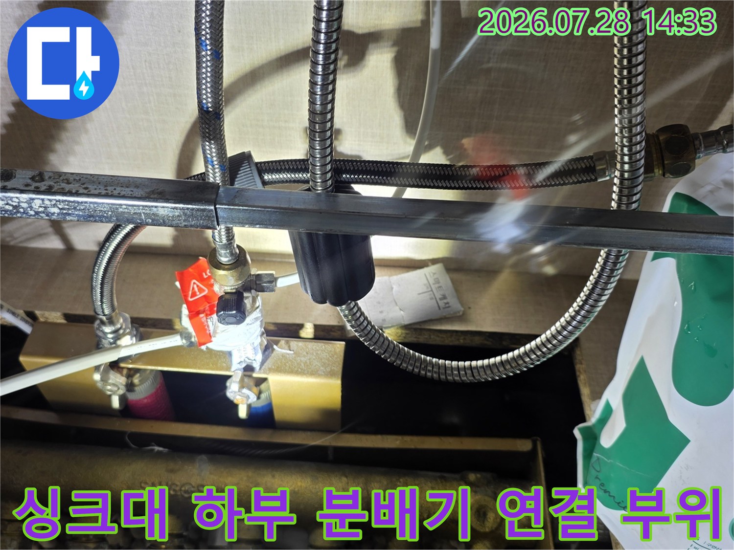 싱크대 아래 설치된 스테인리스 주름관과 빨간색 핸들이 달린 밸브-분배기 연결 상태
