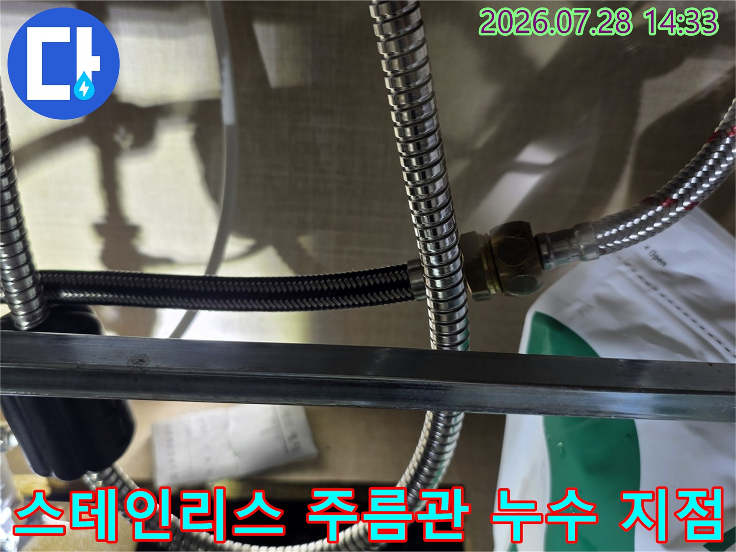 싱크대 하부-금속 주름관 배관이 분배기 너트와 연결되어 있는 모습