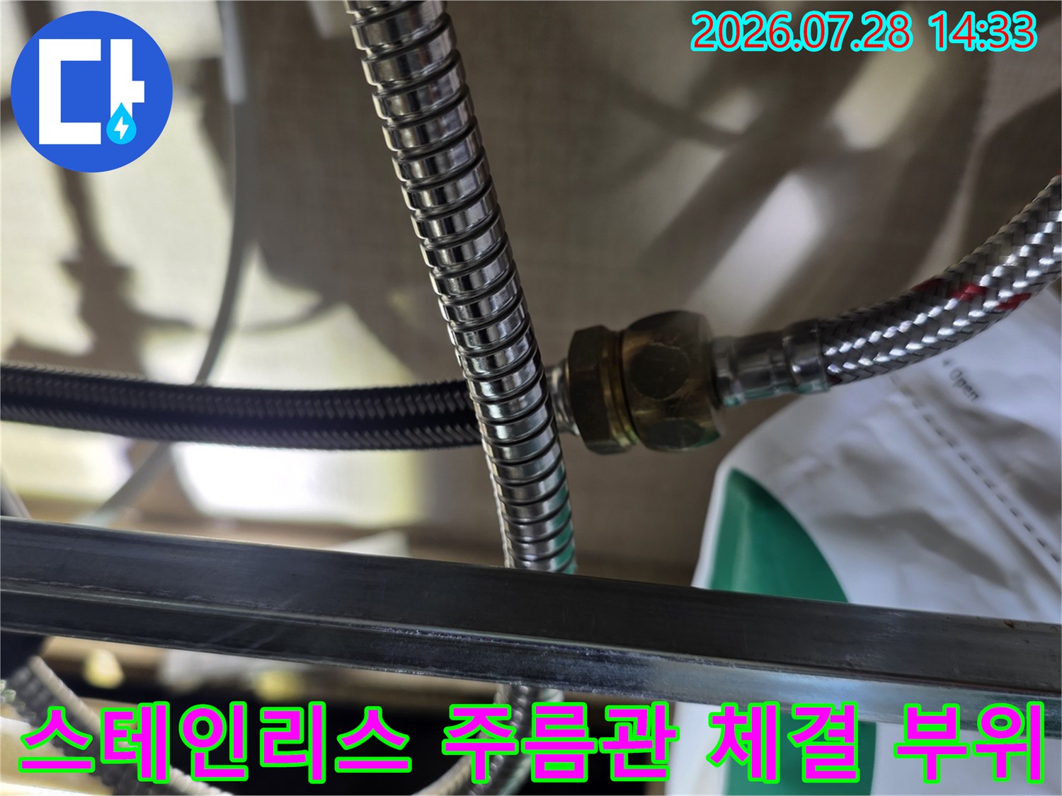 싱크대 하부 배관의 스테인리스 주름관과 금속 너트가 연결된 지점의 모습