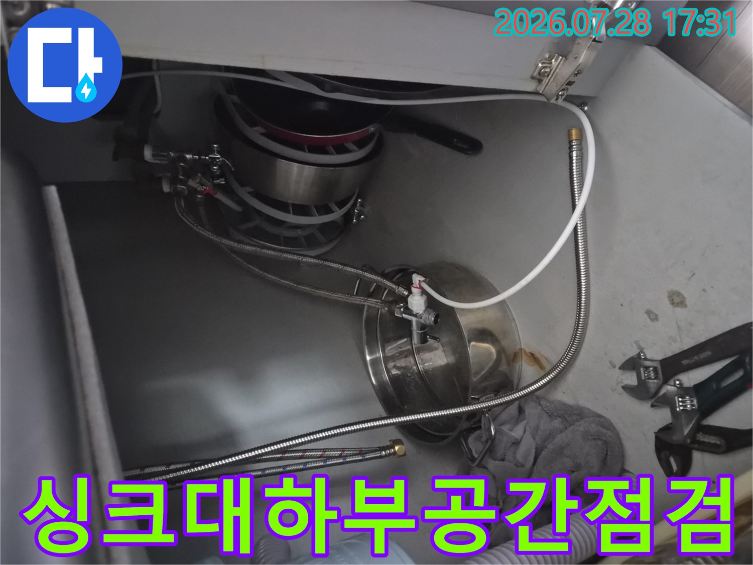 싱크대 하부 공간에서 노출된 배관들의 연결 상태를 세밀하게 확인하는 모습