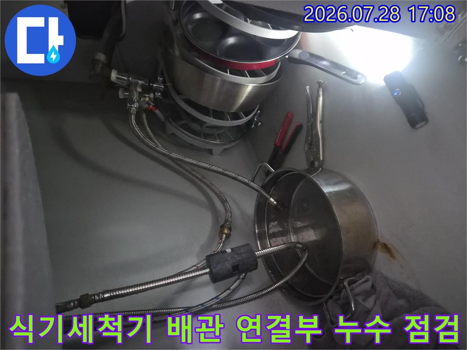 싱크대 하부장에서 식기세척기 연결 부위의 배관 상태를 확인하는 모습