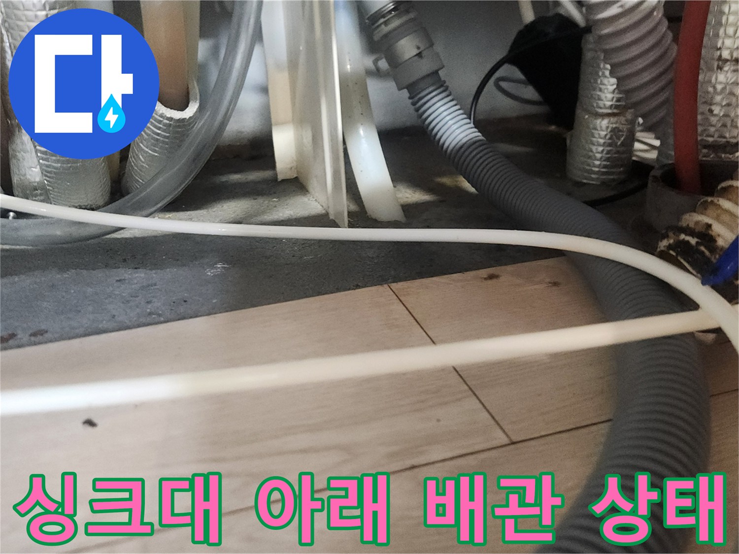 싱크대 밑바닥의 복잡한 배수 호스와 연결 부위 근접 촬영