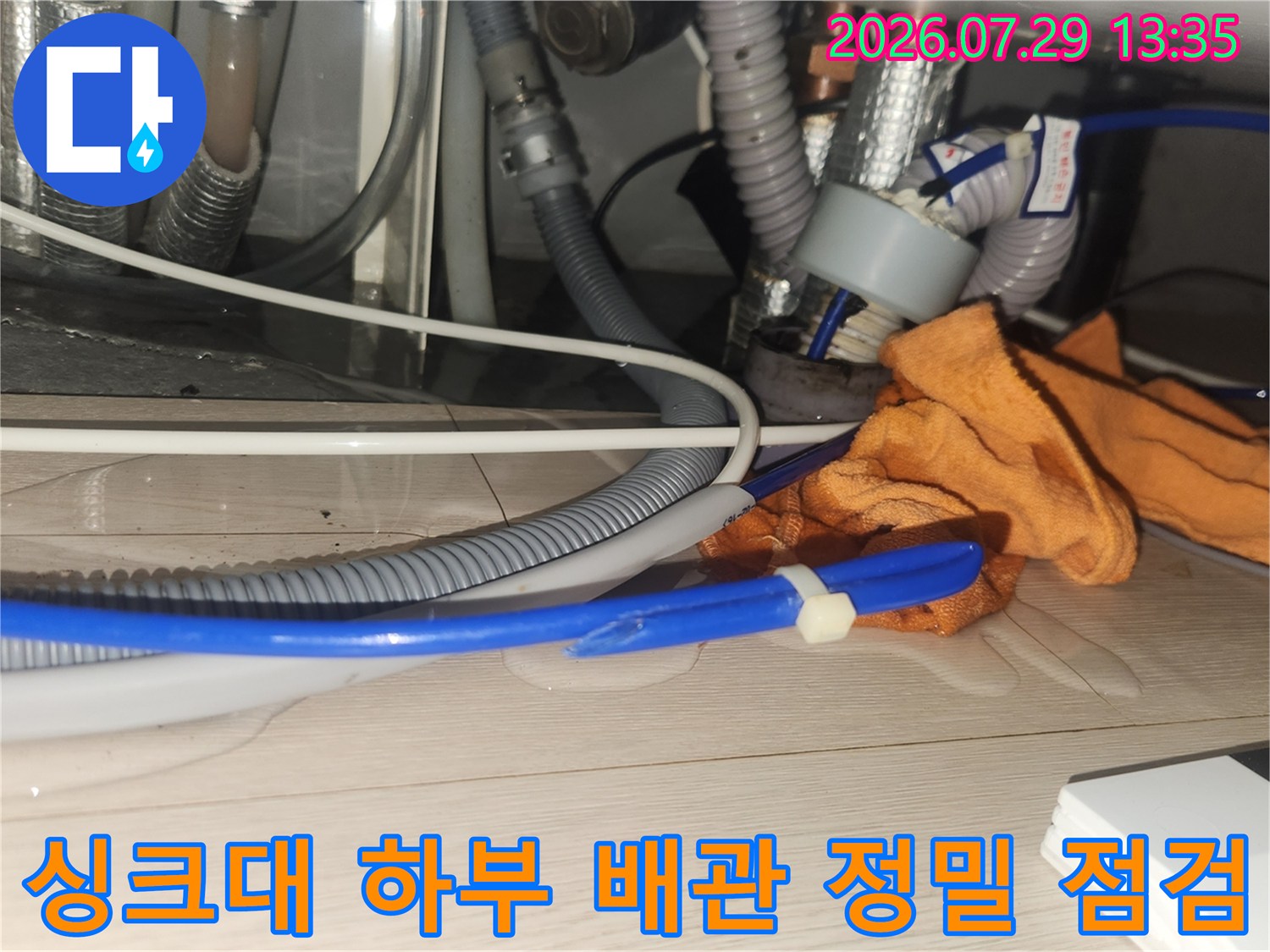 작무공간에 노출된 싱크대용 파란색 호스와 회색 관의 상태를 확인하는 모습