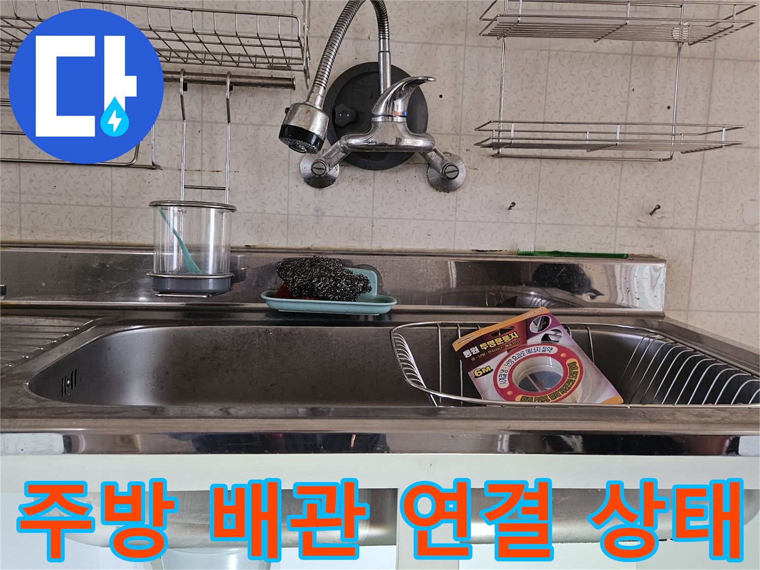 싱크대 아래쪽의 수전 호스와 배수 부속들이 모여있는 모습