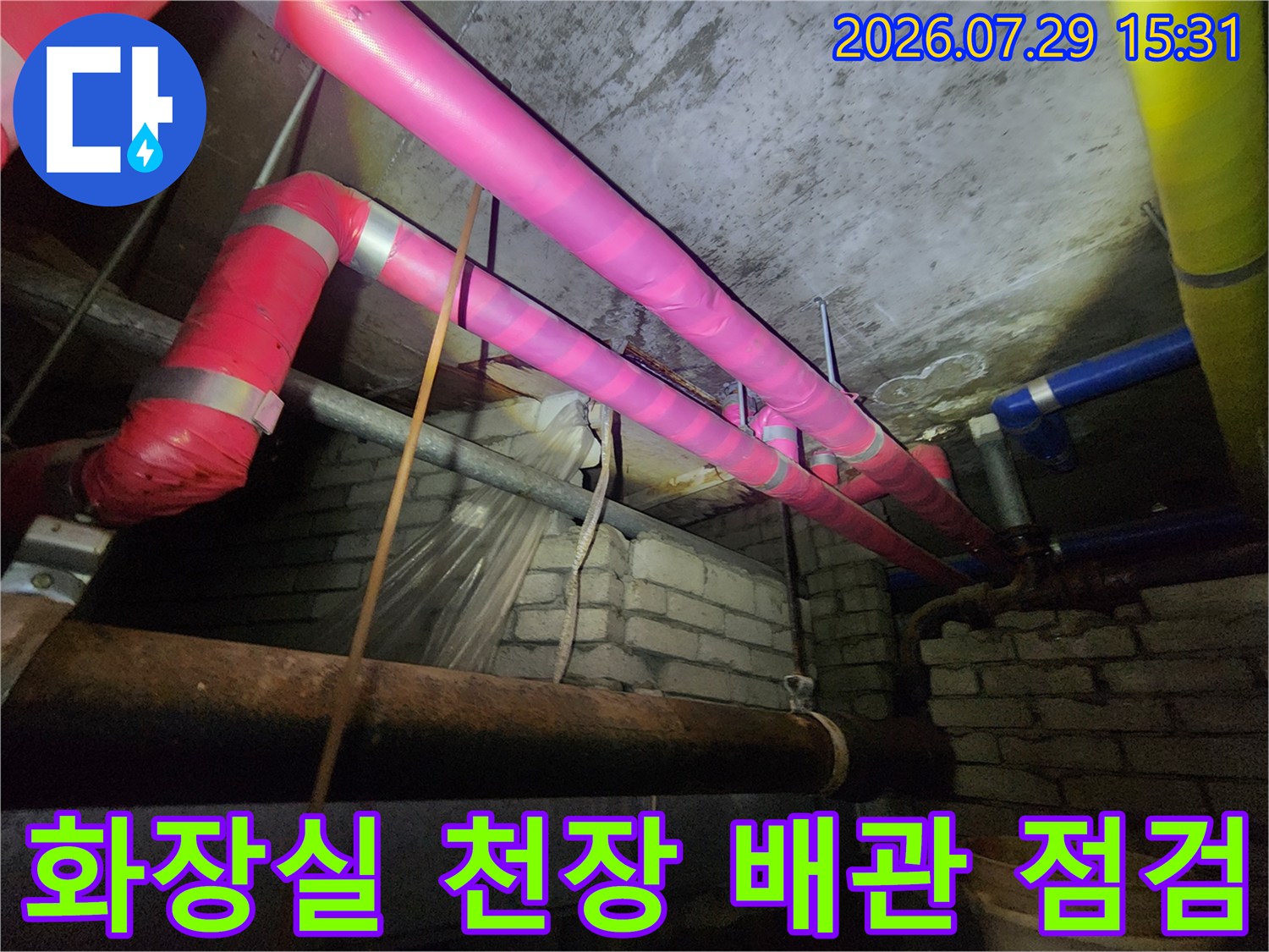 분홍색과 파란색 보온재로 감싸인 화장실 천장 배관 라인을 정밀하게 점검하는 모습