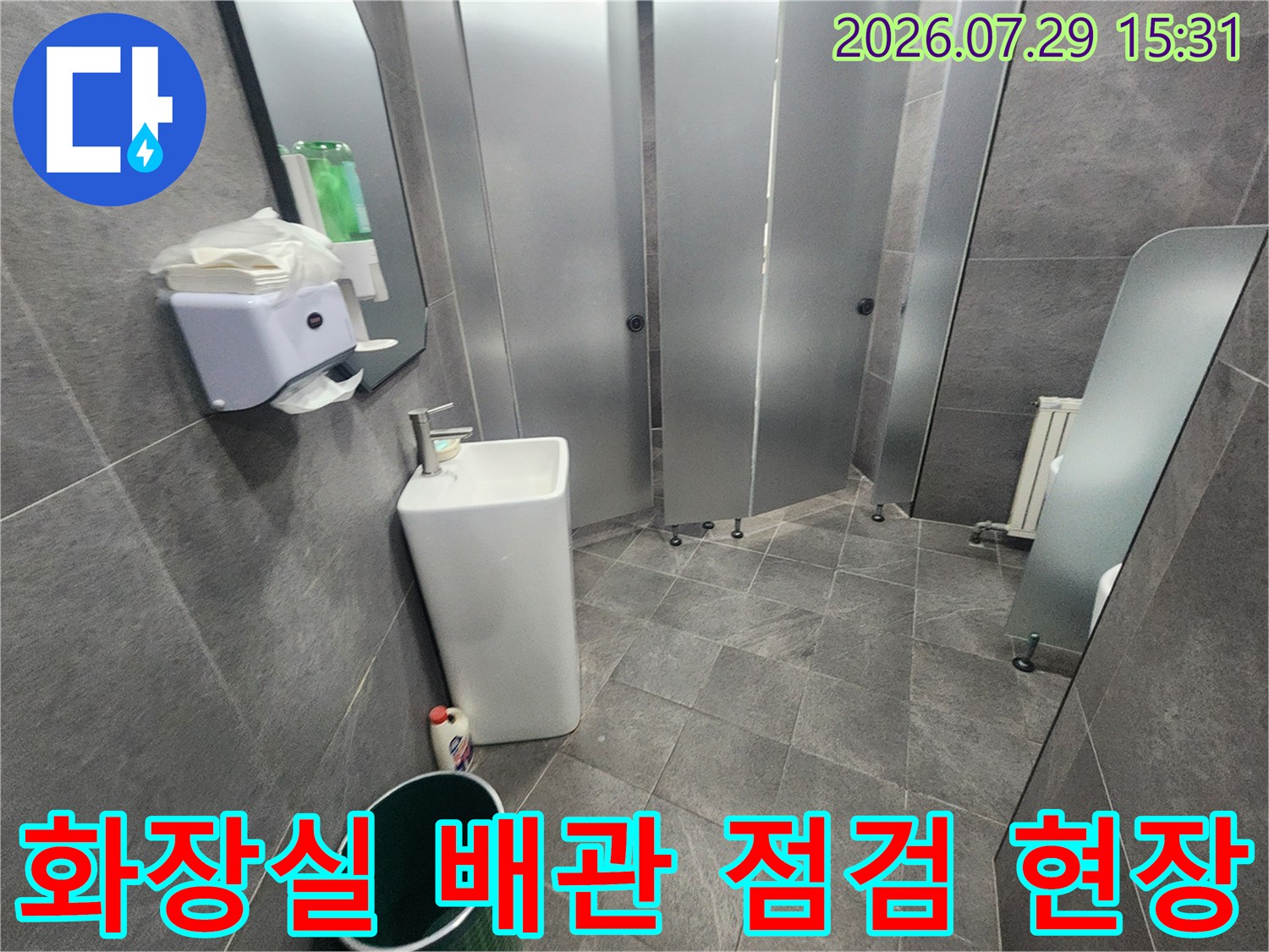 회색 타일로 마감된 화장실 내부와 세면대 및 수전이 설치된 공간 촬영