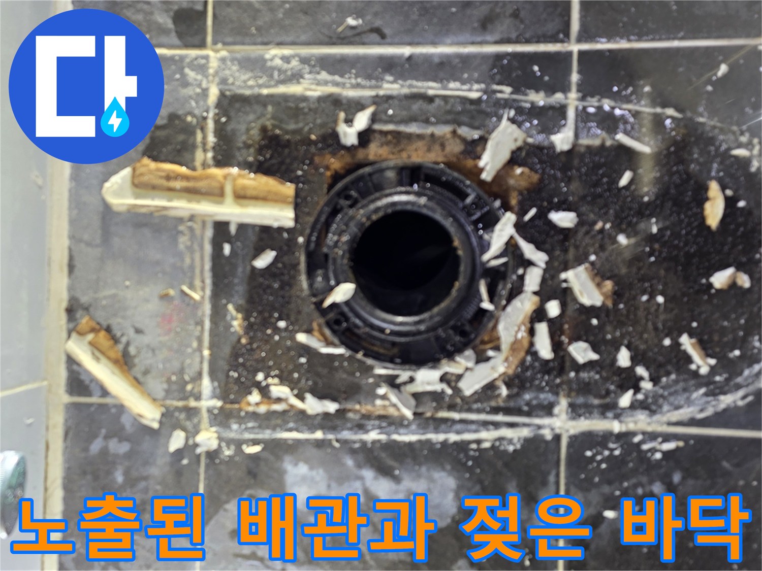 변기 탈거 후 드러난 배수관 입구와 주변 타일 파편