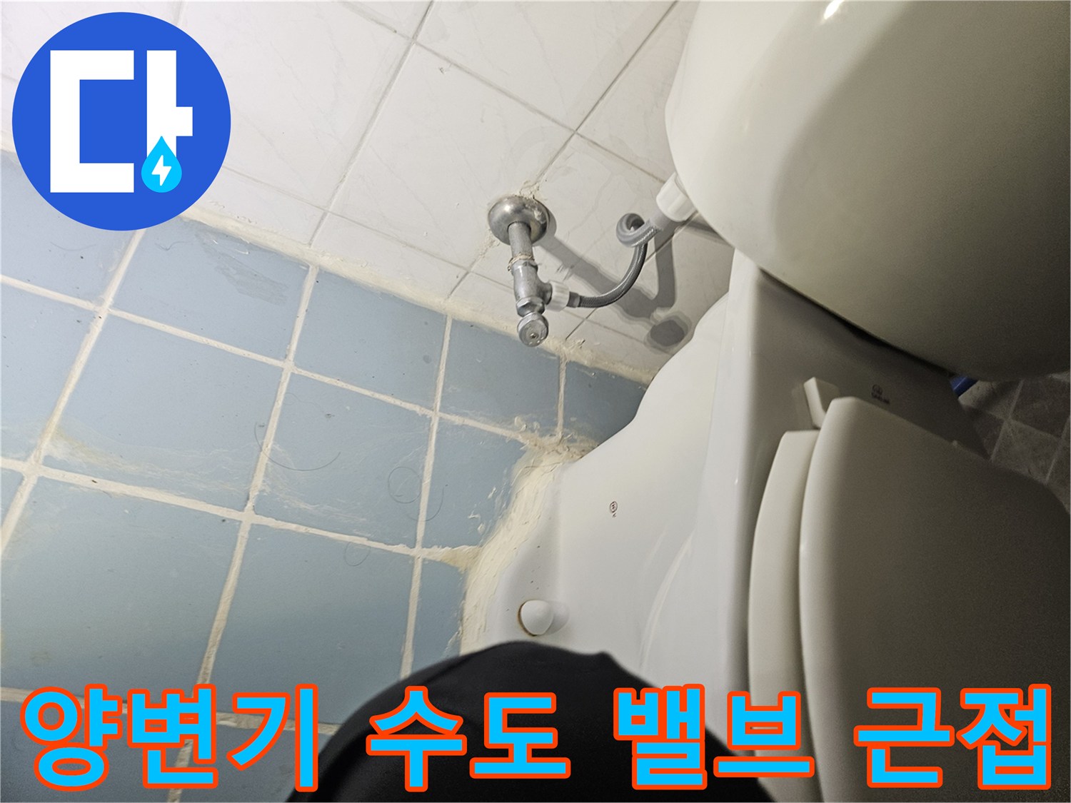 변기 옆쪽 은색 밸브와 타일 사이의 연결 부위를 찍은 사진입니다.