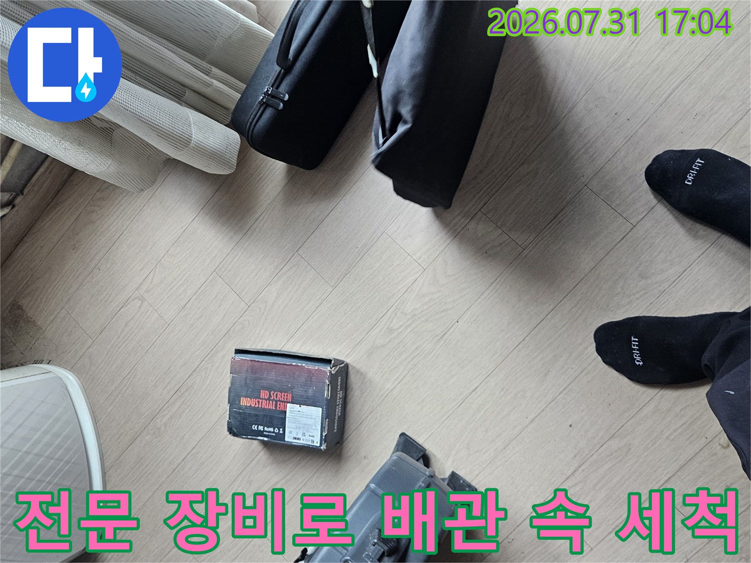 전용 고압세척기와 수동 도구를 활용해 막힌 드레인 호스를 깨끗하게 청소하는 과정