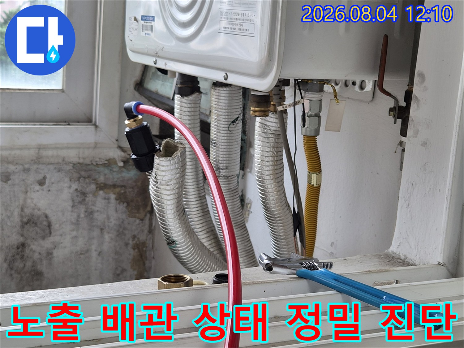 실내기 아래부 하얀색 은박 보온재로 감싼 다수의 배관과 작업용 몽키스패너