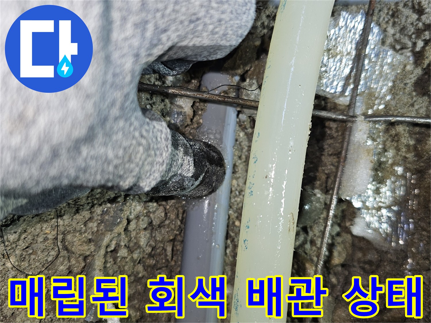 굴착된 바닥 속에서 발견한 손상된 회색 배관과 노출된 연결 부위