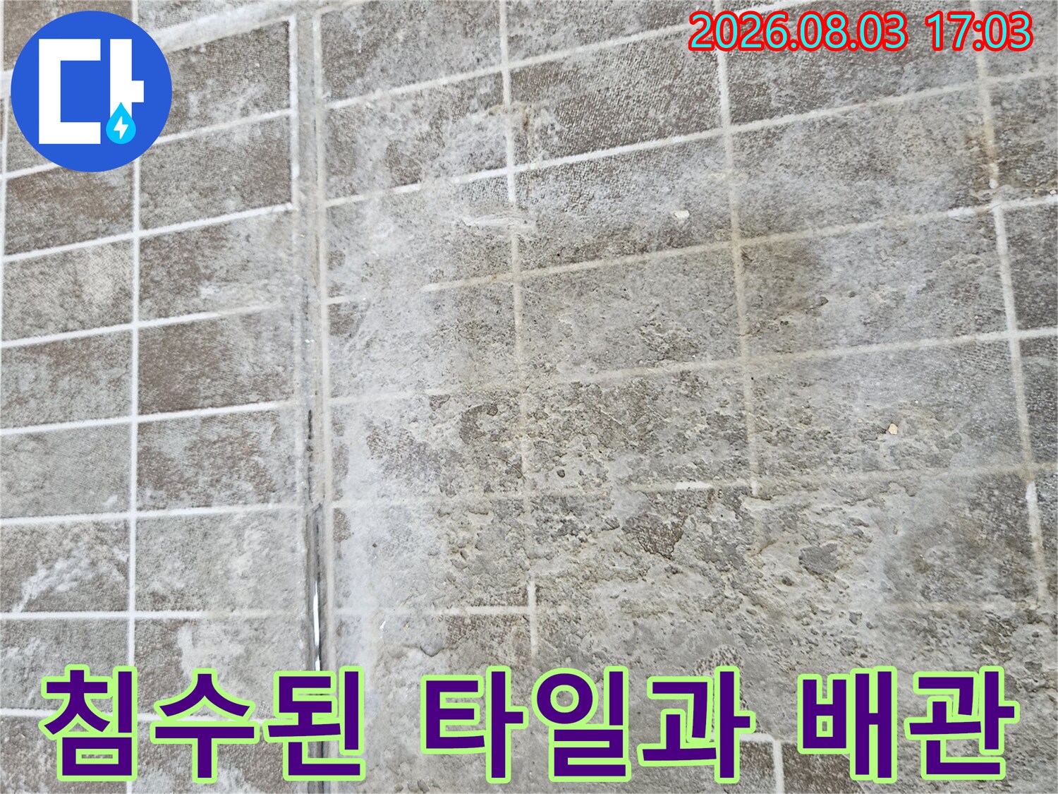 물에 젖어 변색된 타일과 노출된 배관 연결 부위