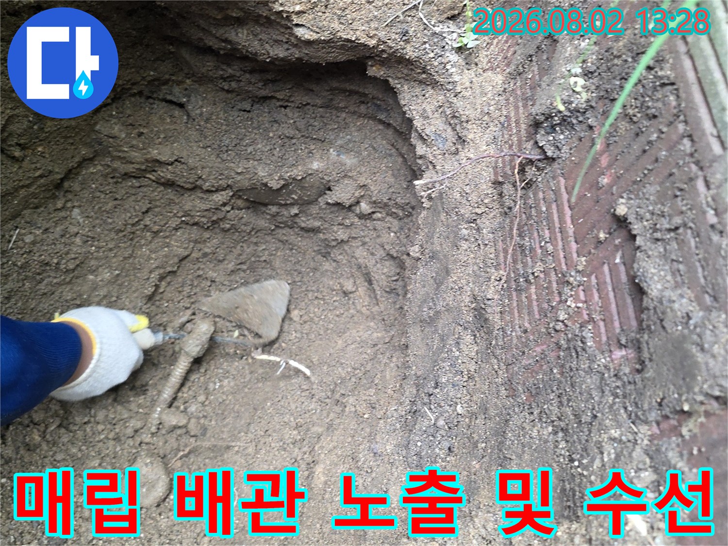 토사 사이에서 드러난 파손 배관과 작업자의 장갑 낀 손