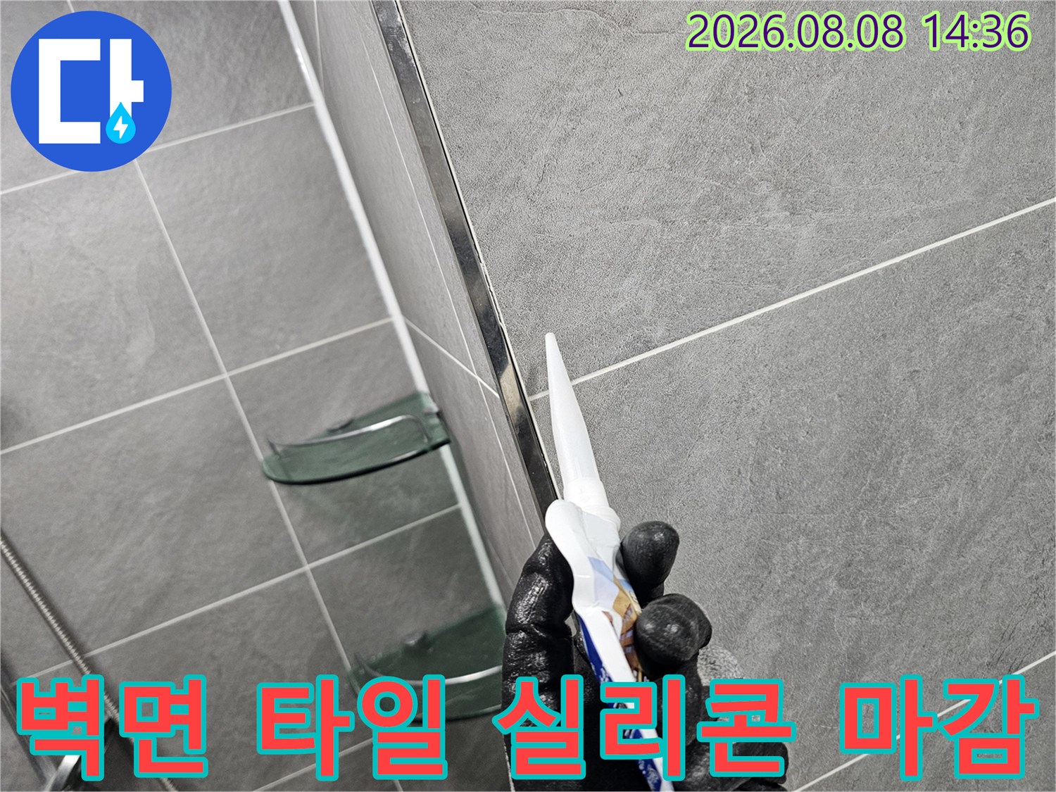 검은 장갑을 낀 엔지니어가 타일 경계에 실리콘을 쏘고 있습니다.
