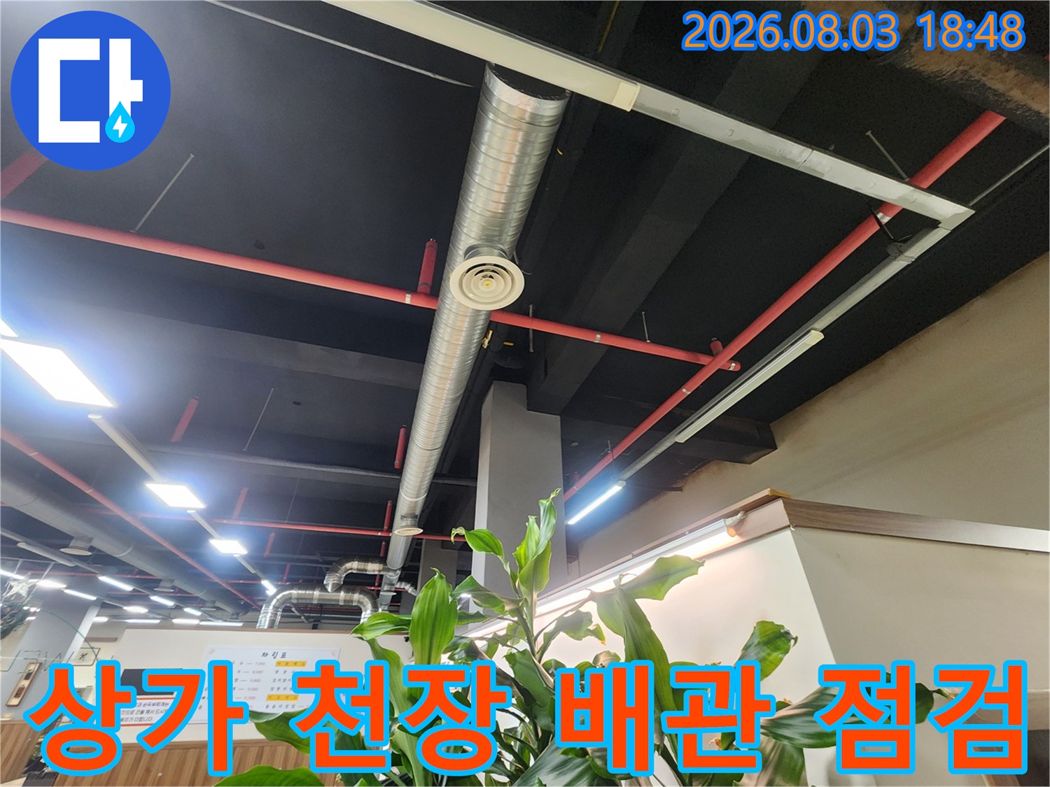 노출된 천장 배관과 소방 설비와 전등이 배치된 실내 모습