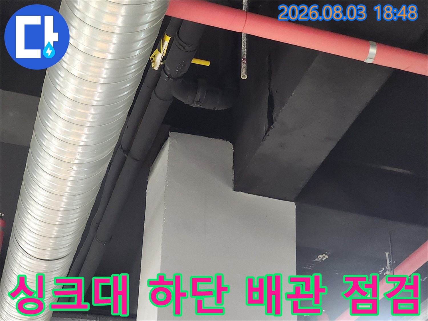 싱크대 아래 노란색과 검은색으로 구성된 복합 배관 구조물 점검