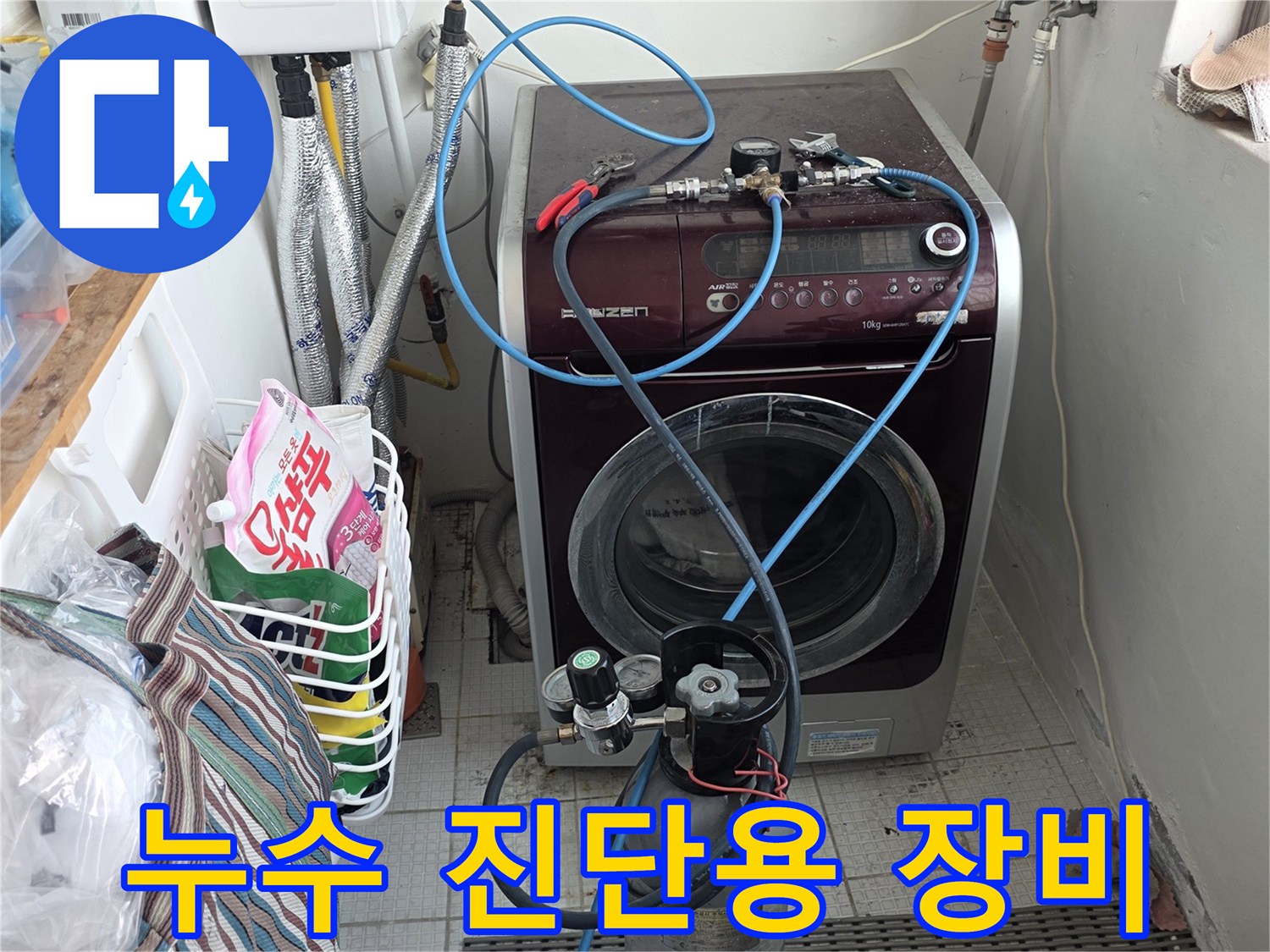 세탁기 옆 배관에 연결된 압력 게이지와 파란색 호스