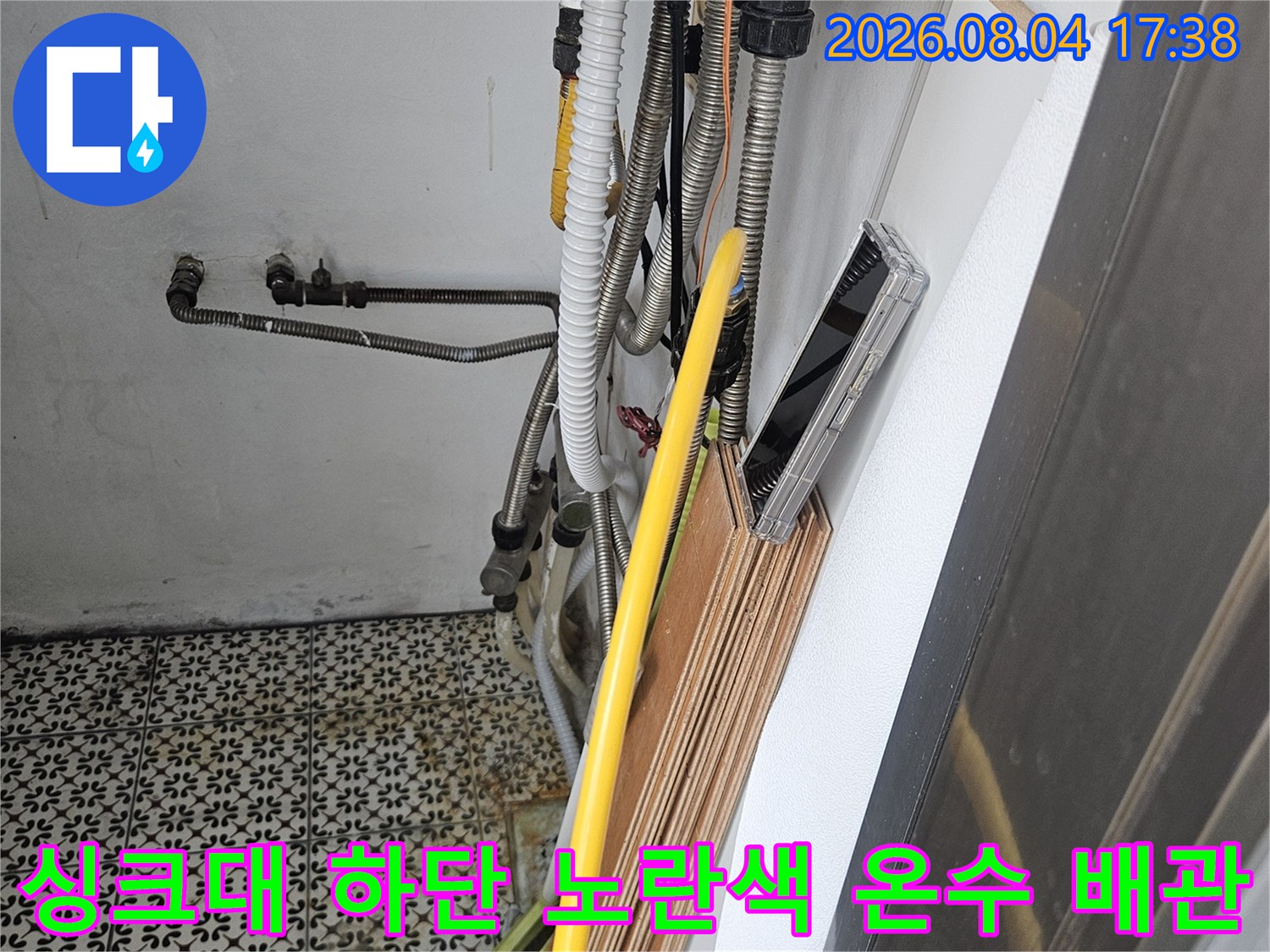 싱크대 아래쪽 공간에 위치한 노란색 보온재로 감싸인 온수 배관 모습