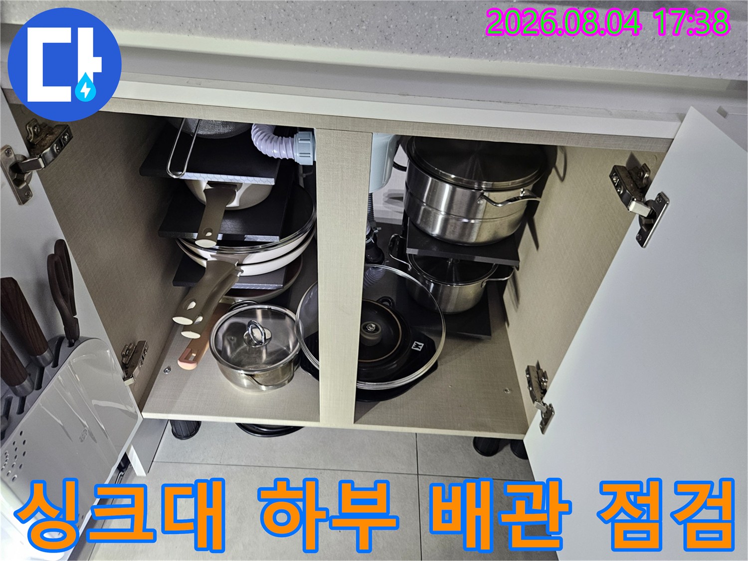 싱크대 하단 수납공간 내부에 노출된 배관과 냄비 등 주방 용품들