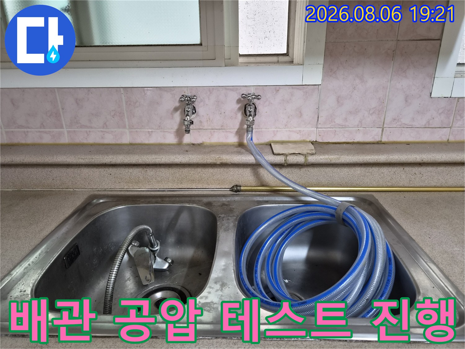 싱크대 수전과 연결된 배관에 파란색 호스를 걸고 압력을 측정하는 모습
