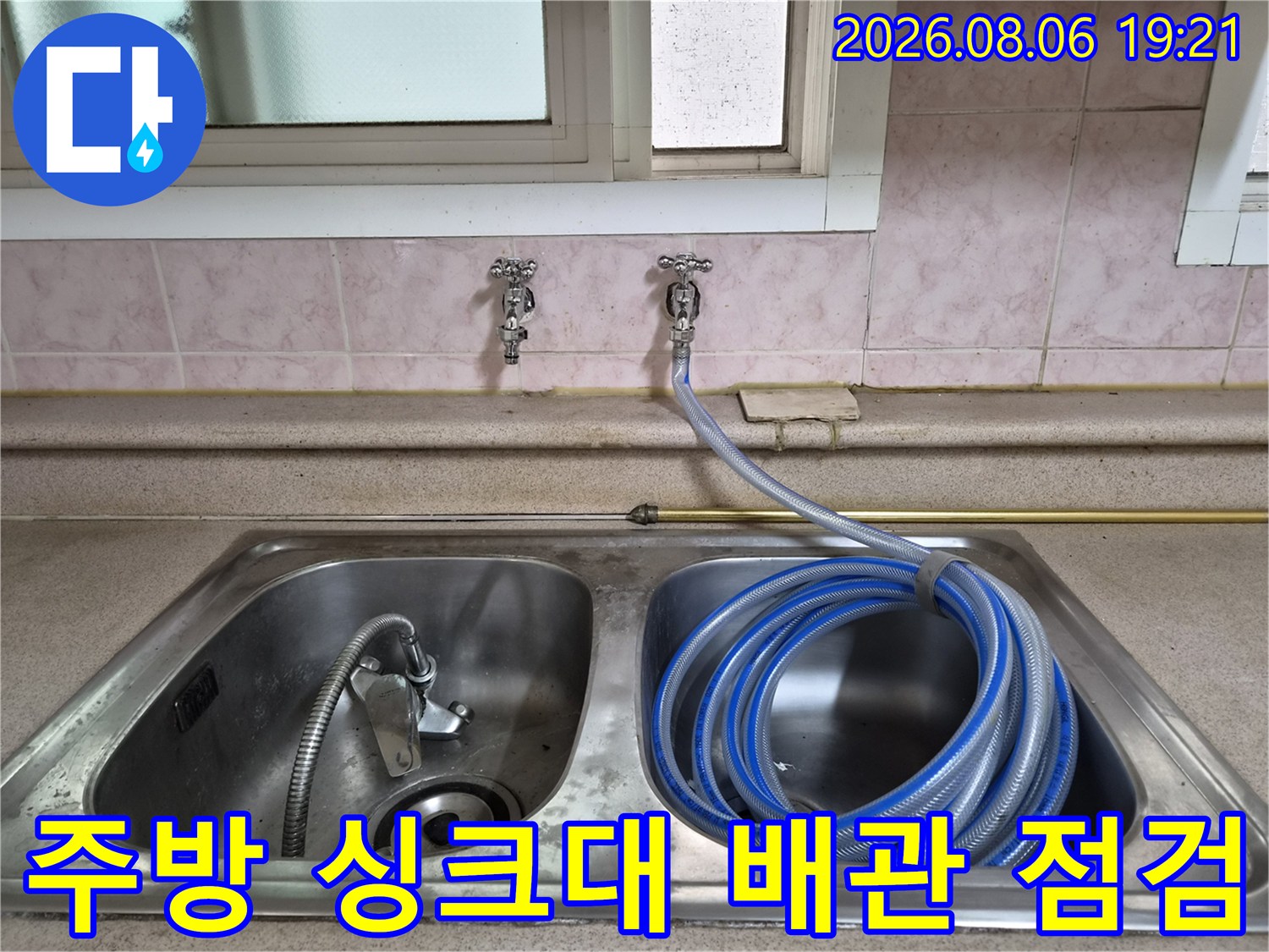 싱크대 아래 위치한 노출 배관에 공압 테스트를 위한 호스를 연결하여 누수 여부를 확인하는 모습