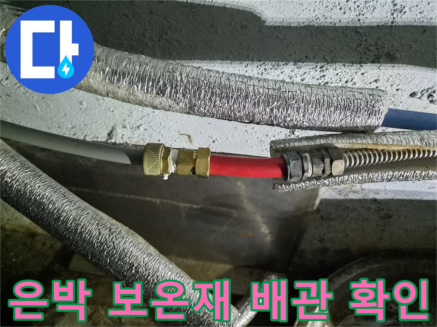 은박으로 감싸진 배관의 빨간색 연결 부위를 면밀히 관찰하는 모습입니다.