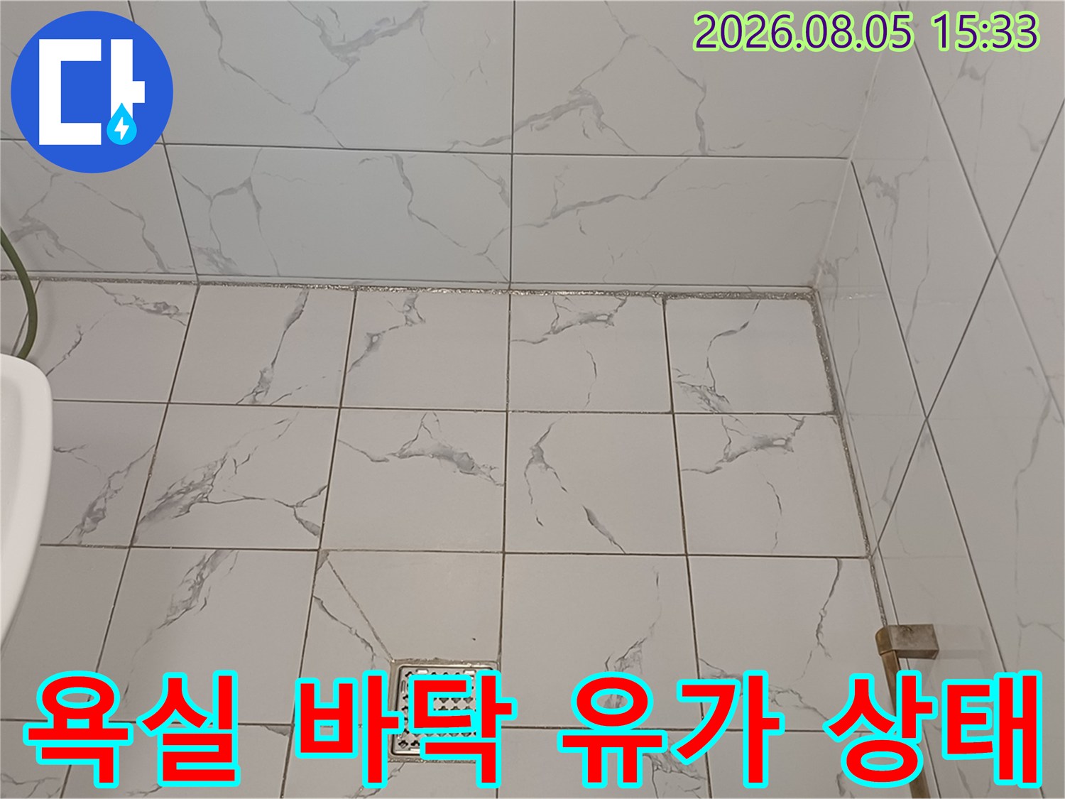 대리석 무늬 타일과 금속 재질의 배수구 덮개 사진