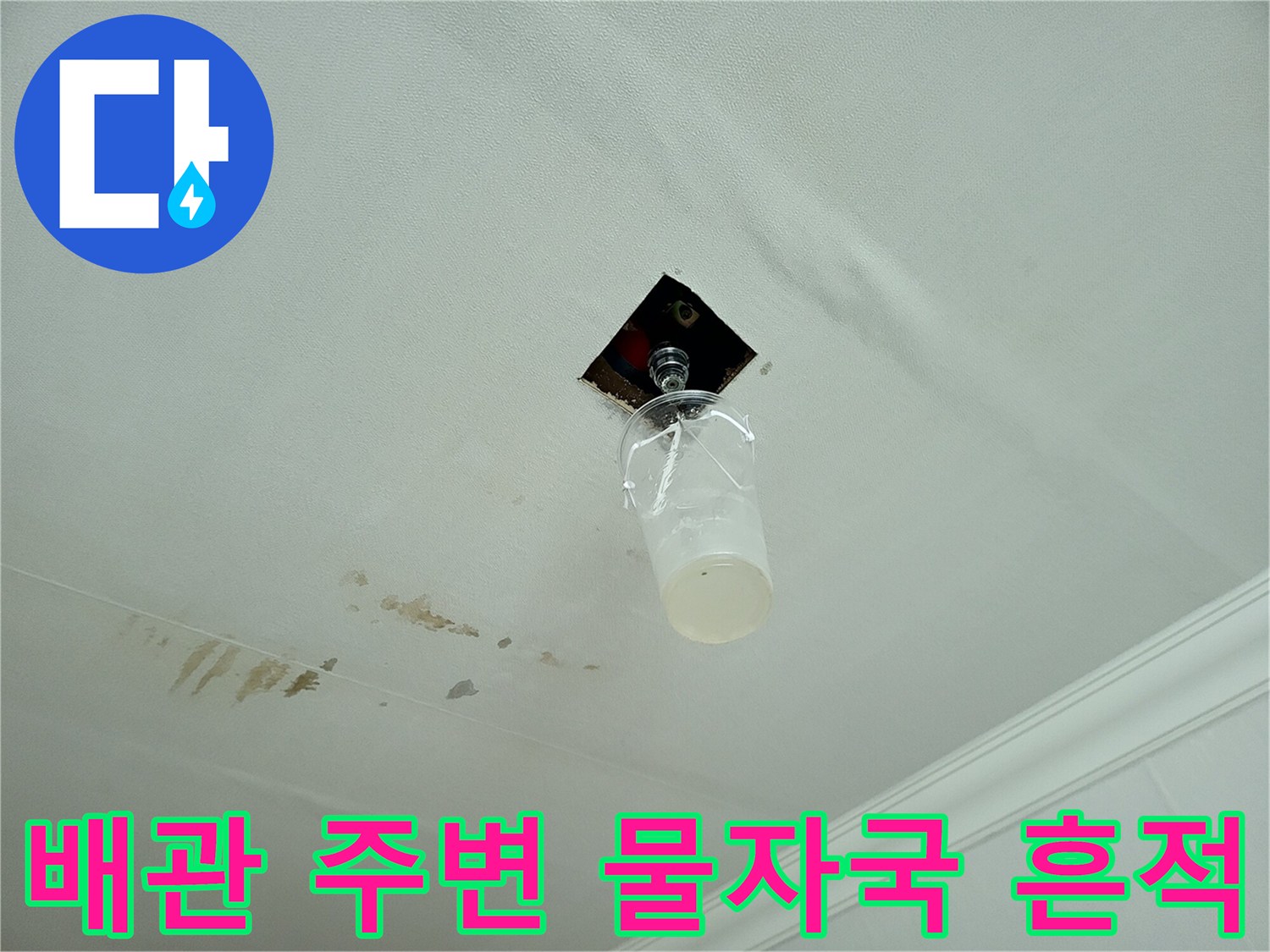천장 구멍 근처에 번진 누수 흔적과 노출된 배관 일부