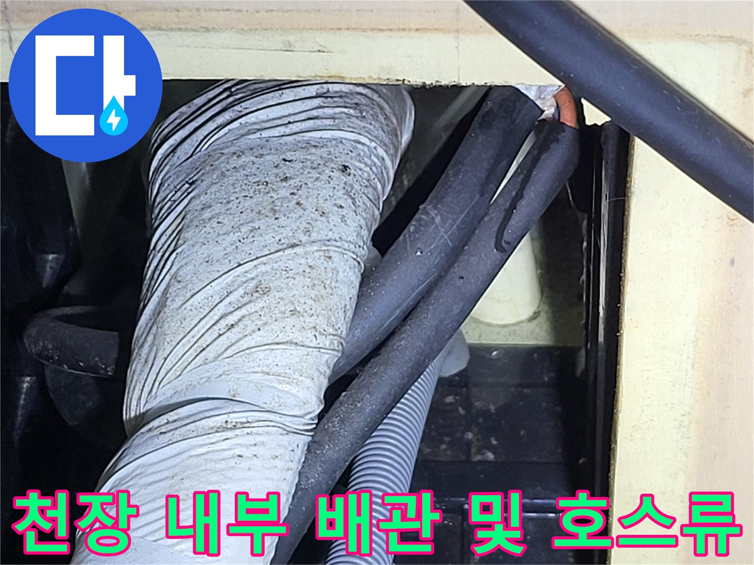 하얀 보온재 배관과 회색 주름관이 지나가는 천장 내부 공간