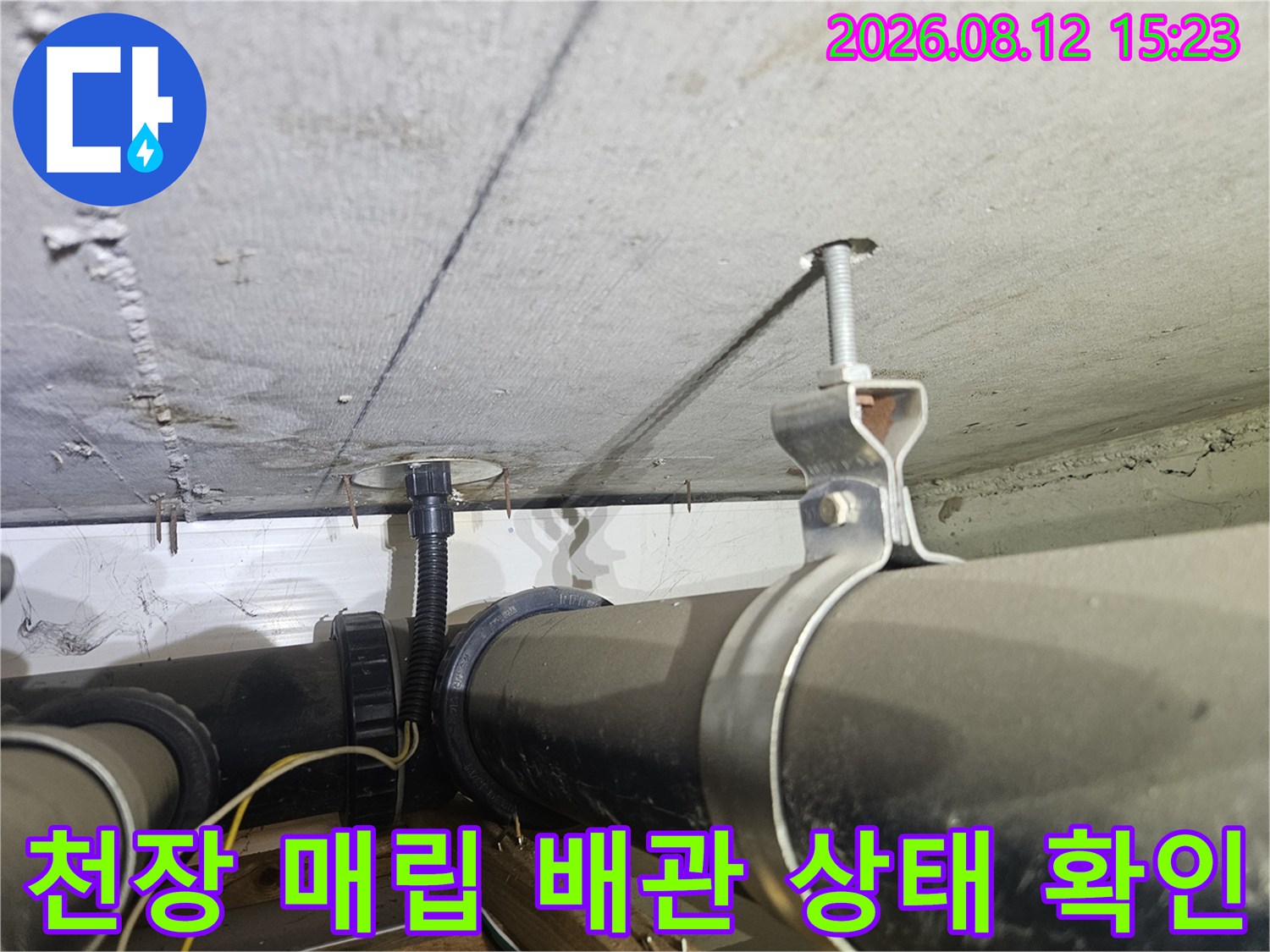 콘크리트 천장에 설치된 검은색 PVC 배관과 지지용 볼트-클로즈업