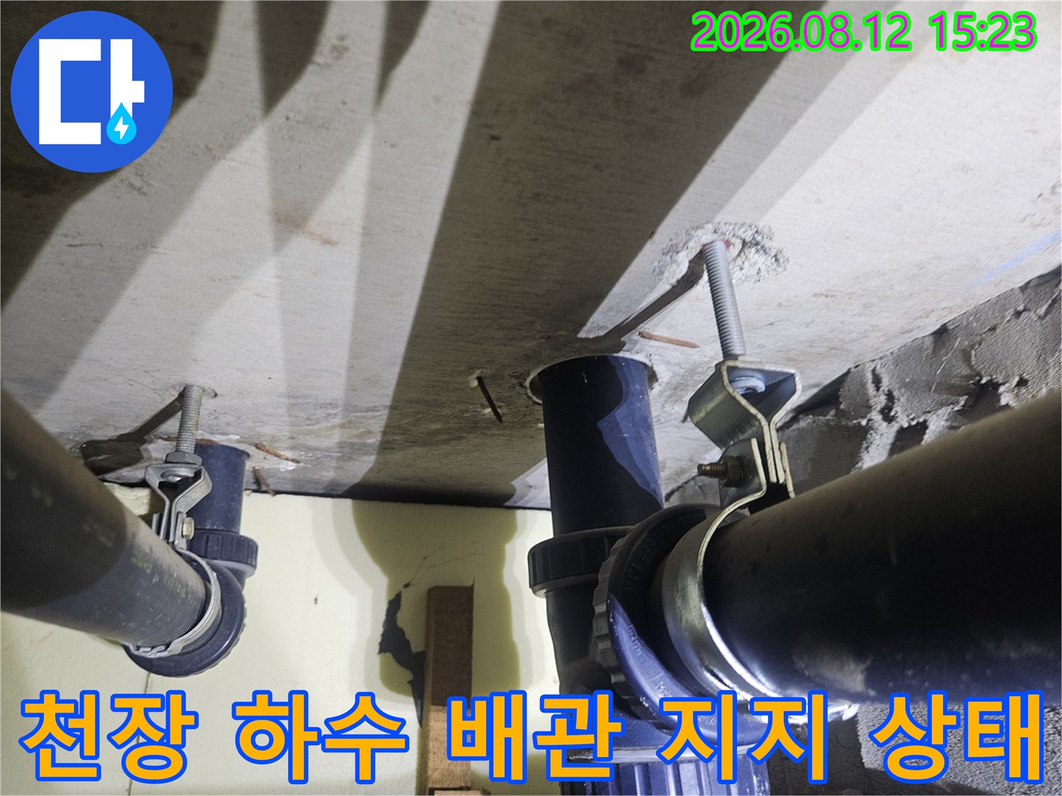 콘크리트 천장에 전산볼트로 고정된 검은색 플라스틱 하수관의 연결 부위 모습