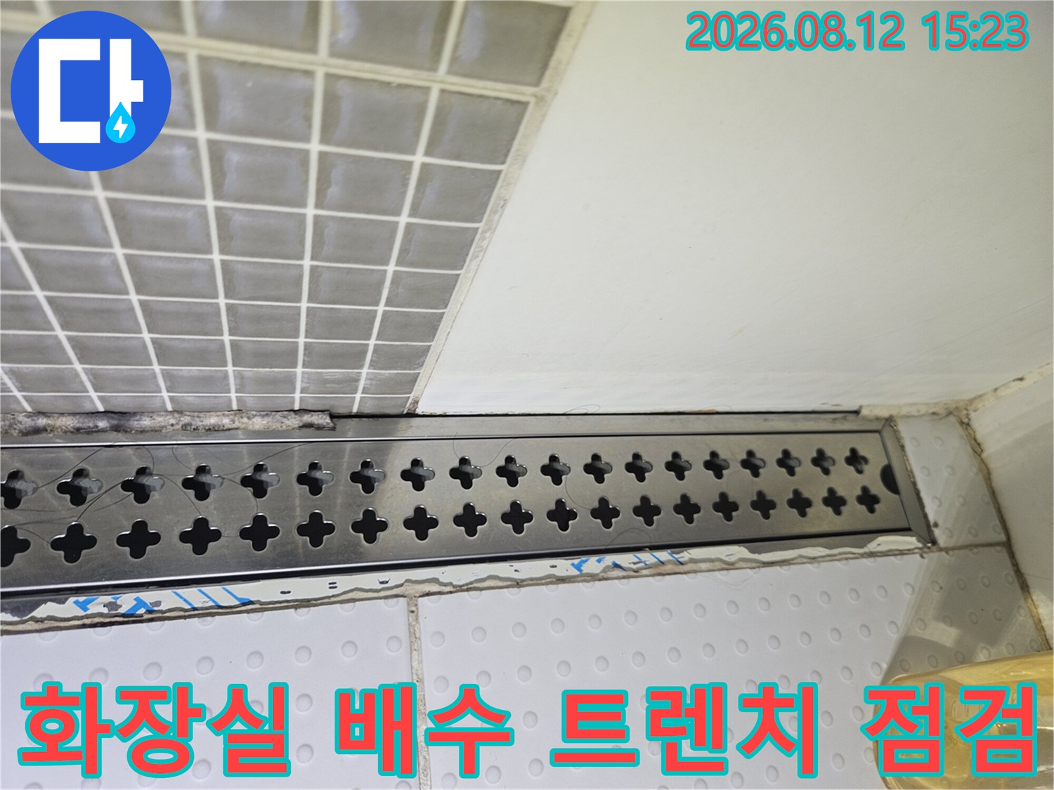 화장실 바닥의 스테인리스 소재 긴 배수 트렌치와 타일 마감 부위-누수 점검 모습