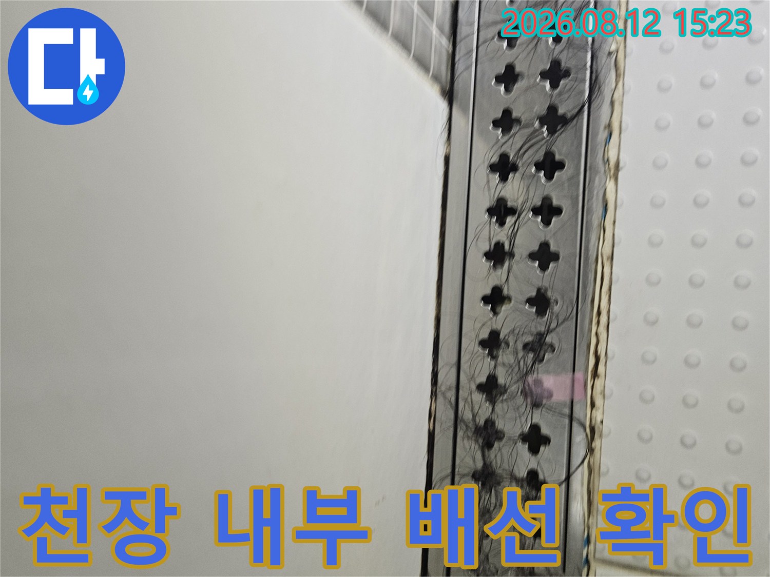 흰색 천장 패널 아래 설치된 검은색 통풍구-내부 전선 뭉치 노출 상태