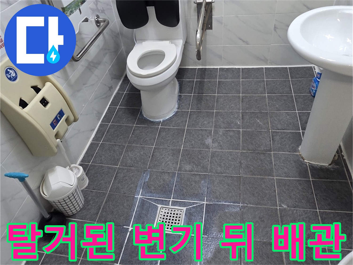 양변기를 들어낸 후 보이는 젖은 타일과 배수구 주변 모습입니다.
