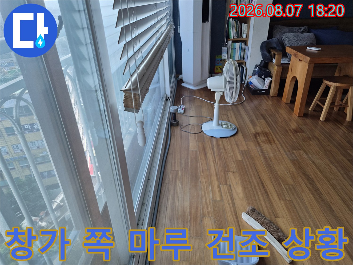 에어컨 배수 문제로 젖은 거실 마루 바닥을 선풍기로 말리고 있는 현장 모습