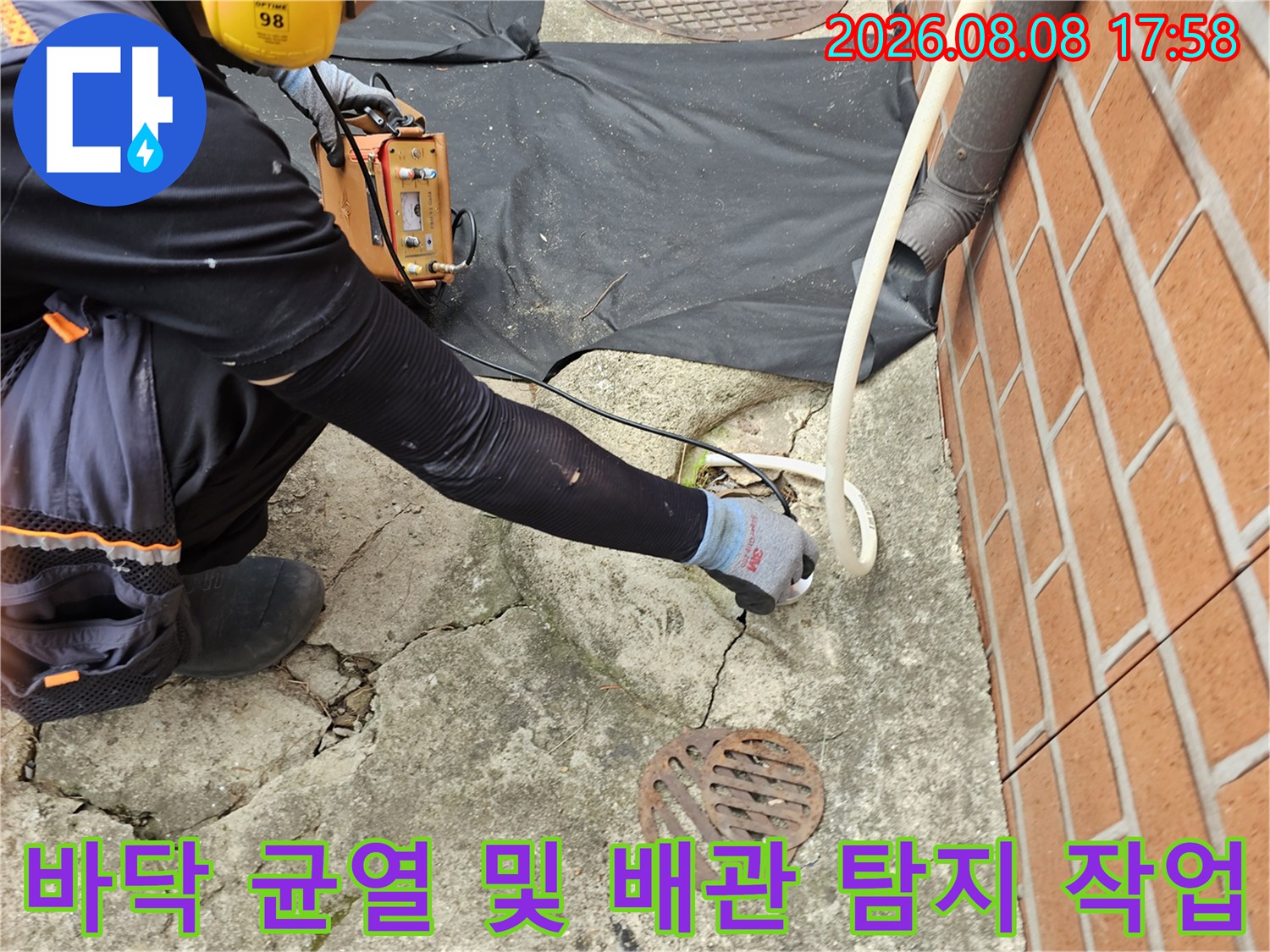 갈라진 지면과 맨홀 근처에서 진행되는 배관 누수 정밀 검사 장면