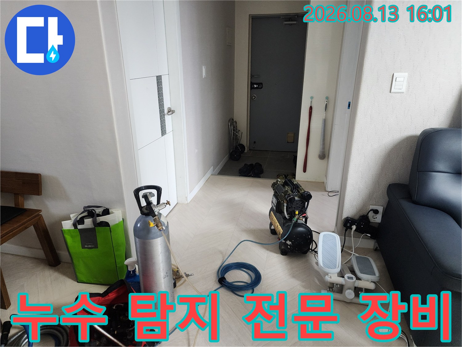 아파트 거실에 배치된 누수 진단용 가스통과 공기 압축기 세트