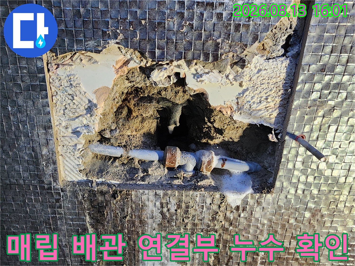 타일 틈새로 드러난 노후된 수도 배관과 부식된 연결 부위