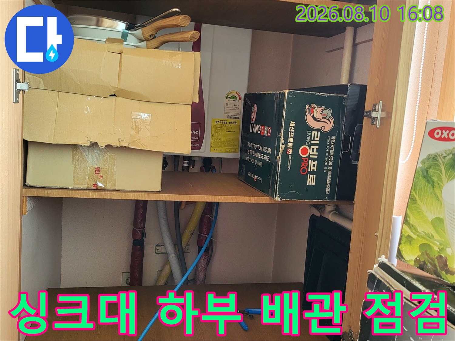 싱크대 하부장 내부의 배관과 주변 물건들의 모습입니다.