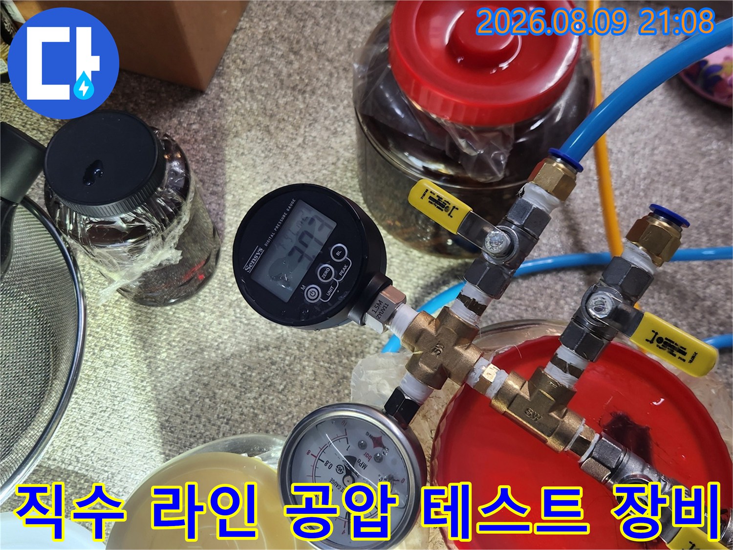 파란색 호스와 황동 밸브 그리고 디지털 압력계가 연결된 누수 검사 장치