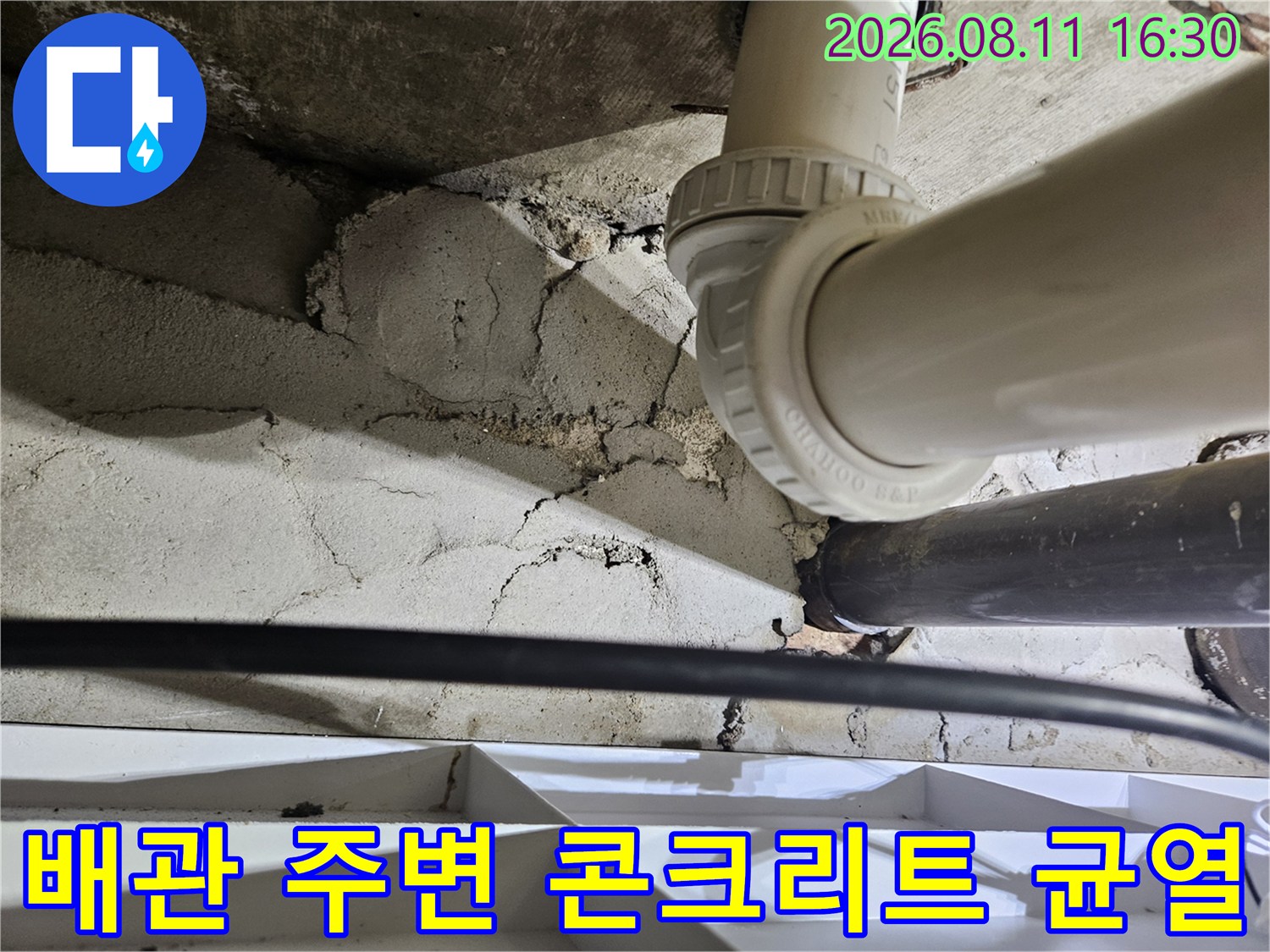 배관 연결 부위 주변의 갈라진 콘크리트와 습기 젖은 표면
