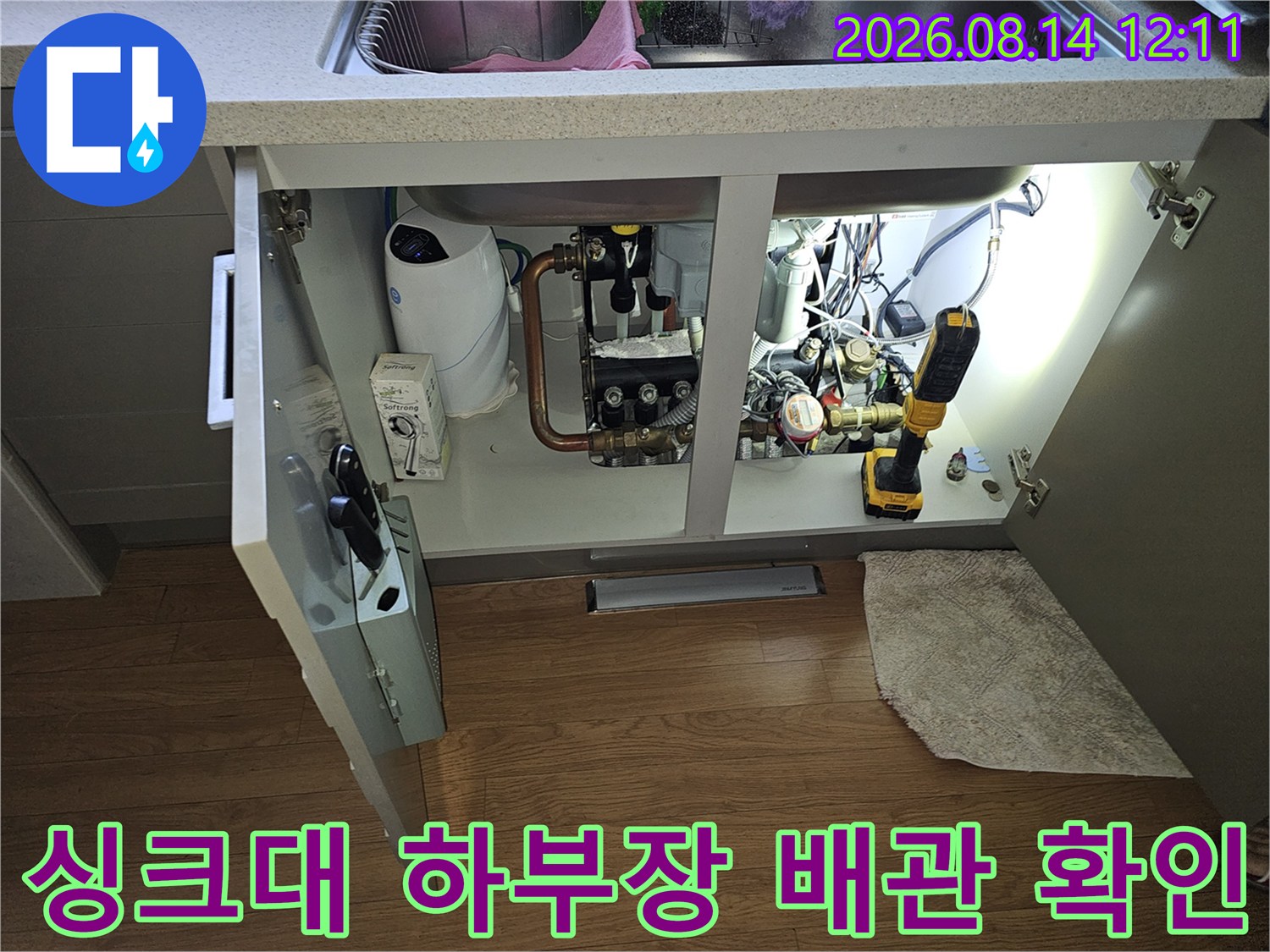 싱크대 하단 공간의 수도 계량기와 각종 밸브 및 배관 연결 상태를 점검하는 모습