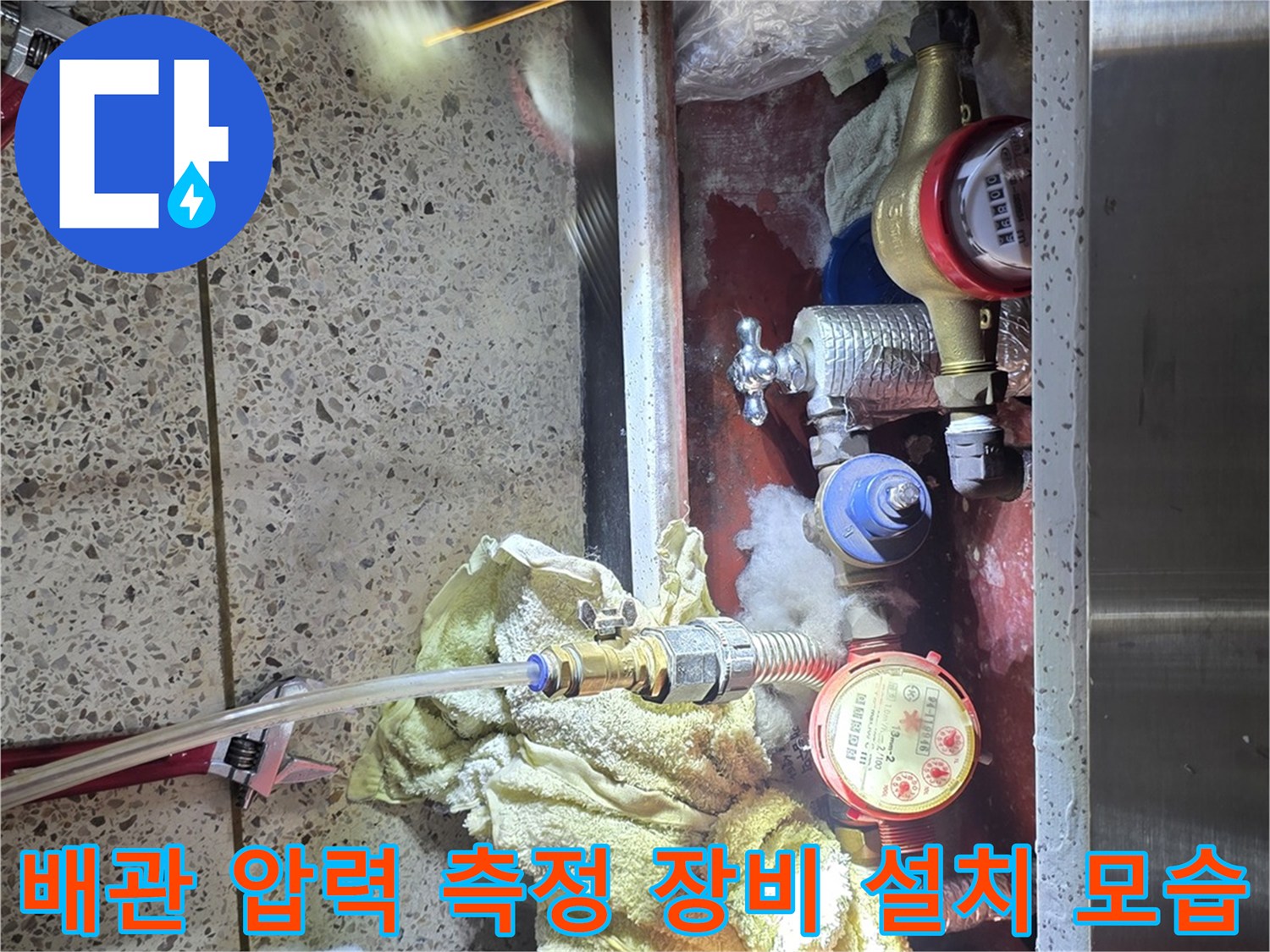 배관-시스템에-체결된-원형-압력계와-작업용-조명이-함께-보이는-사진