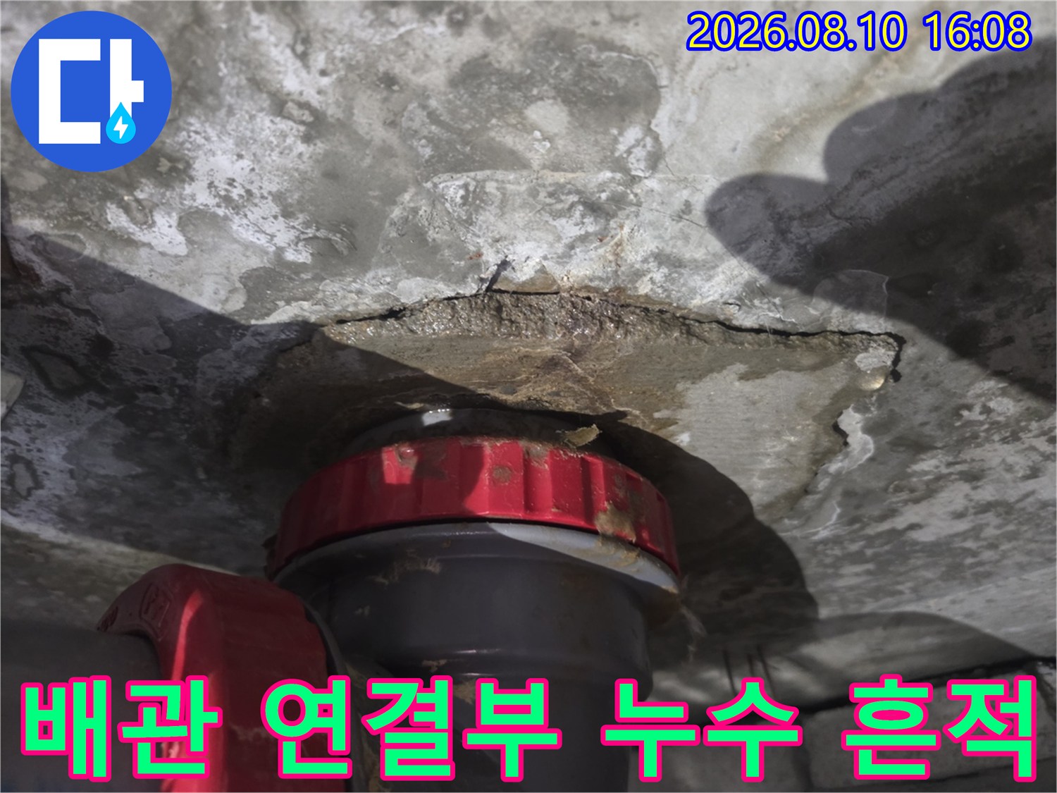 천장 배관 부속 주변의 젖은 콘크리트와 누수 자국을 촬영했습니다.