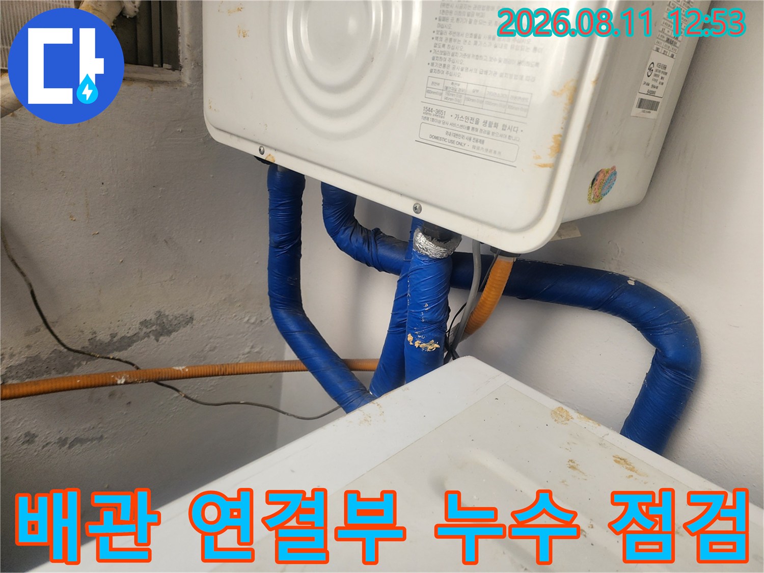 보일러 하단-파란색 배관 보온재와 벽면의 오염된 상태를 근접 촬영