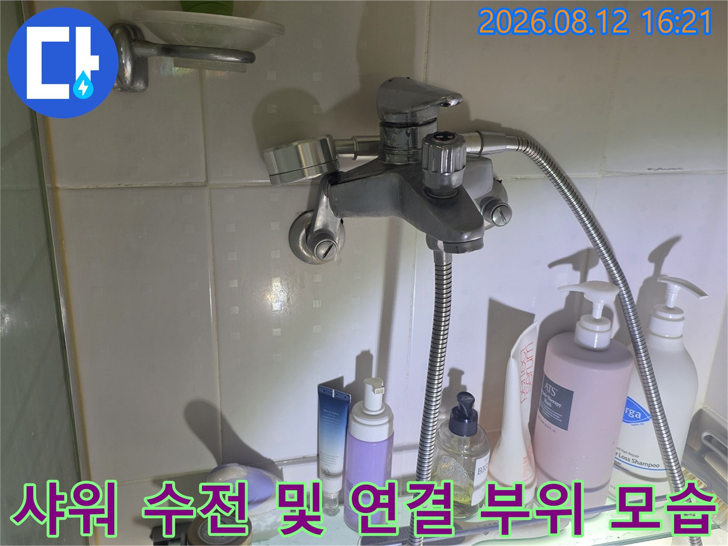 욕실 벽면에 설치된 금속제 수전과 그 아래 배치된 세면 용품들