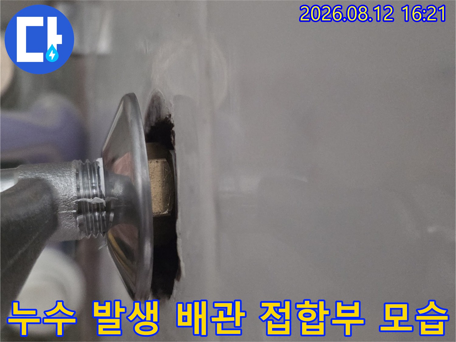 흰색 천장재 아래로 돌출된 금속제-배관 연결 커넥터의 근접 사진