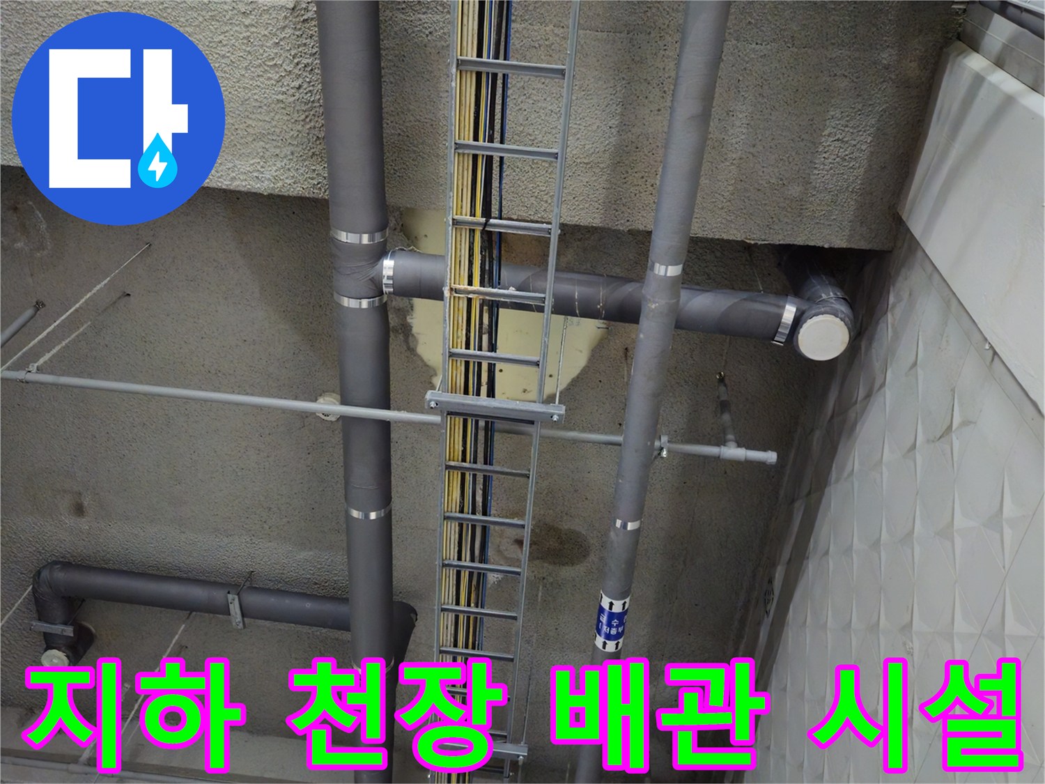 상업용 건물 지하 주차장의 노출된 배관 및 케이블 트레이 구조